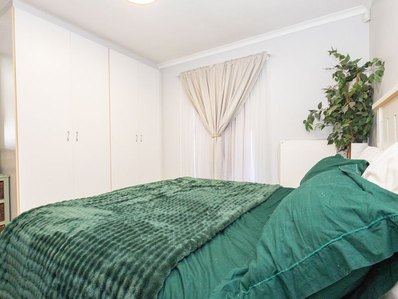 A bedroom featuring built-in cupboards and neutral wall finishes, providing a functional and well-lit sleeping space.