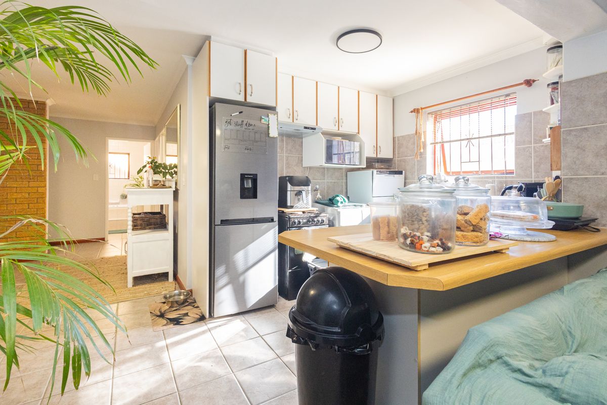 A functional kitchen featuring built-in cabinetry, tiled backsplash, and a breakfast counter, providing a practical layout for daily meal preparation.
