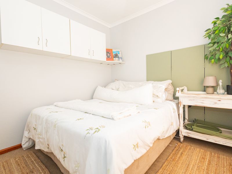 A compact bedroom featuring built-in overhead storage cabinetry and neutral wall finishes.
