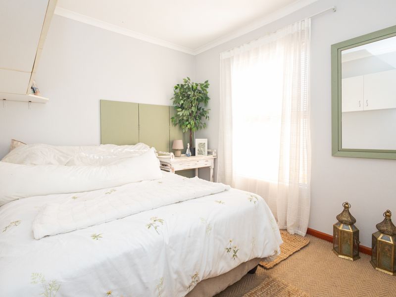 A bright bedroom featuring neutral walls, carpeted flooring, and built-in shelving, offering a comfortable and functional living space.