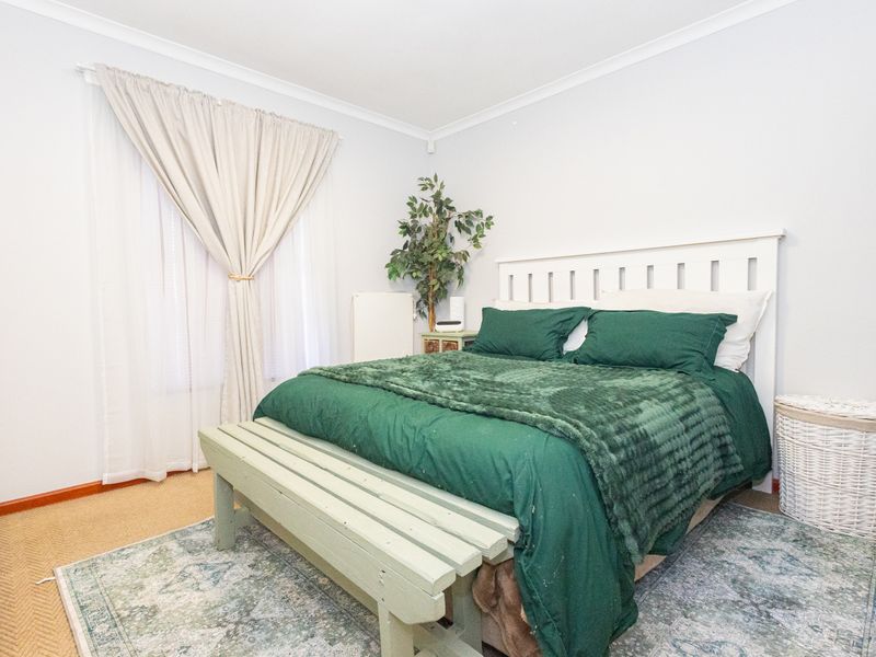 A well-lit bedroom featuring neutral wall finishes, carpeted flooring, and a built-in wardrobe, offering a comfortable and functional living space.