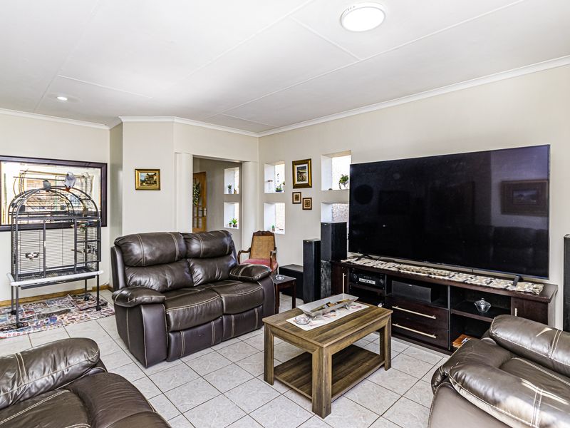 A spacious living room featuring tiled flooring, coved ceilings, and unique recessed wall niches, providing a functional and comfortable living space.