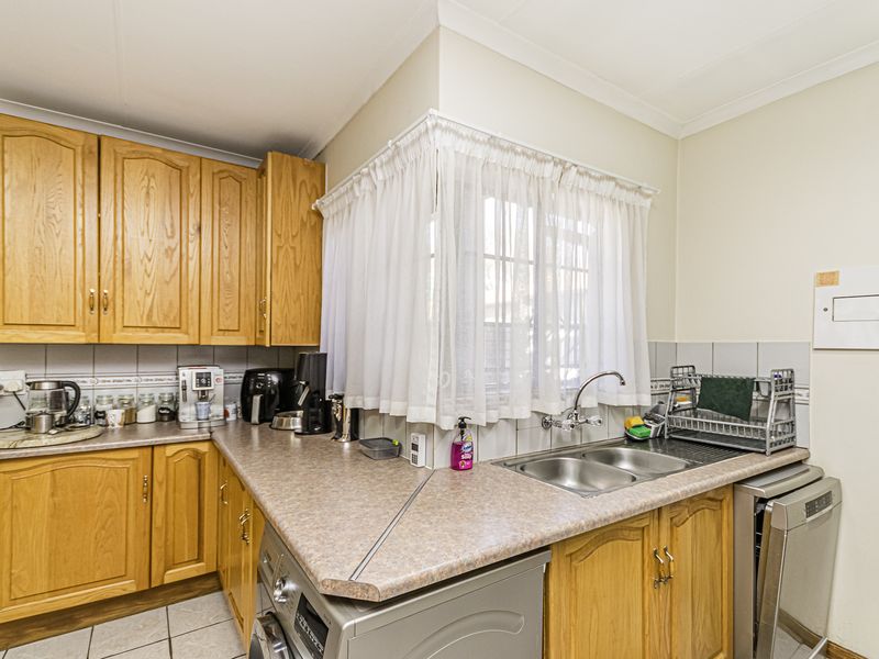A functional kitchen featuring timber cabinetry, laminate countertops, a double bowl stainless steel sink, and tiled backsplash.