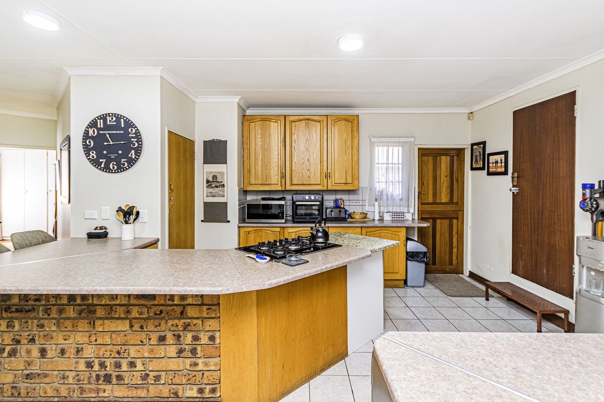 A functional kitchen featuring wooden cabinetry, laminate countertops, a brick-faced breakfast bar, and tiled flooring, offering a traditional layout with ample storage space.