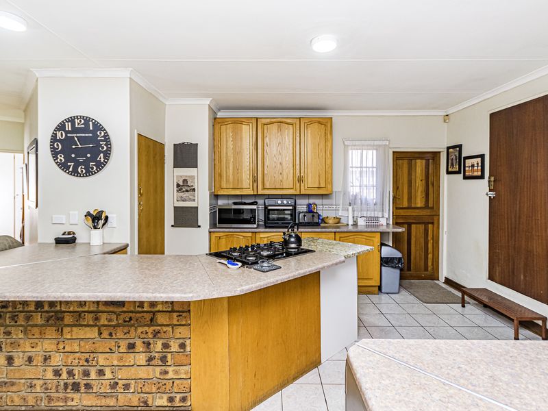 A functional kitchen featuring wooden cabinetry, laminate countertops, a brick-faced breakfast bar, and tiled flooring, offering a traditional layout with ample storage space.