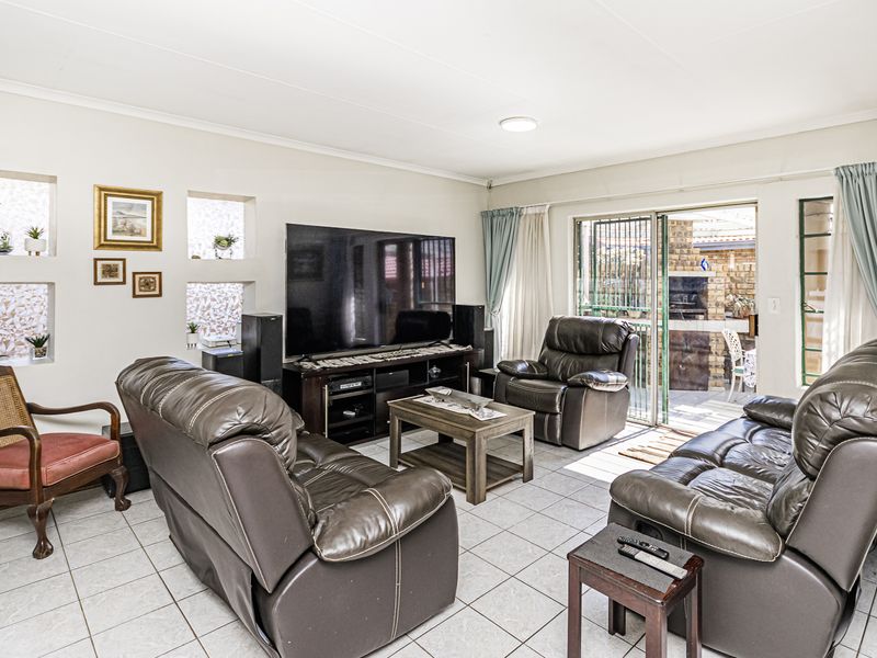 A spacious living room featuring tiled flooring, recessed wall niches, and a sliding glass door providing direct access to the outdoor patio area.