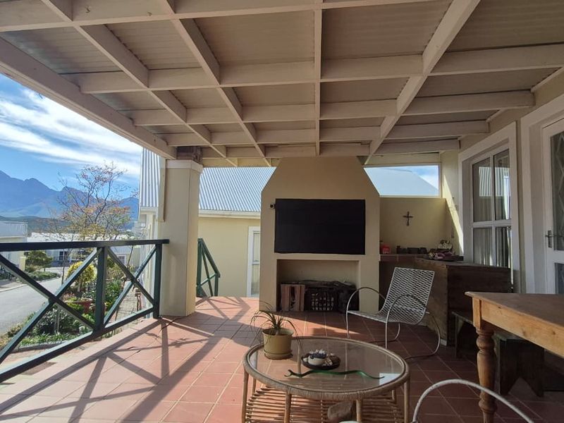 Covered patio featuring a built-in braai, tiled flooring, and a timber pergola roof, offering mountain views and direct access to the home.