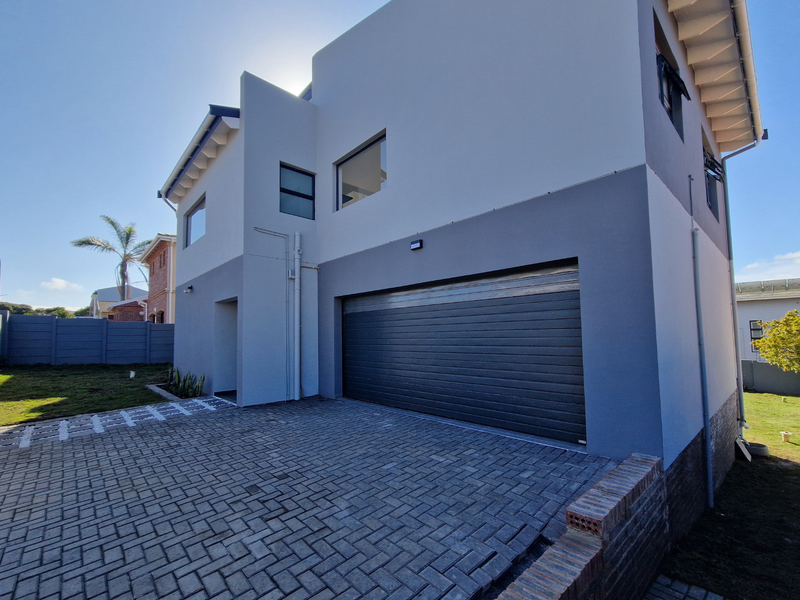 Modern double-storey home exterior featuring a paved driveway, secure double garage, and clean contemporary architectural lines.
