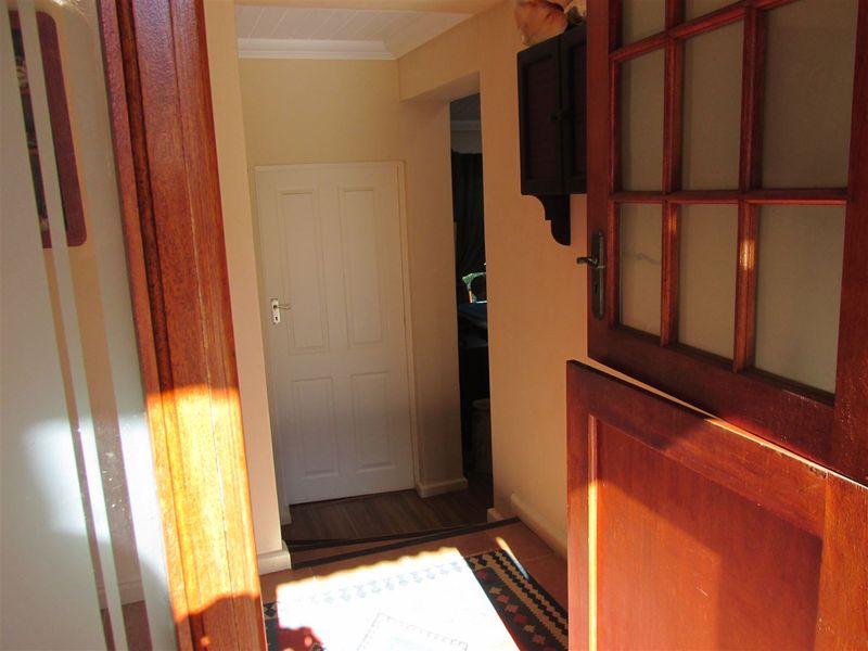 A functional hallway featuring timber door frames, a panelled interior door, and coved ceiling details, providing access to adjacent rooms.