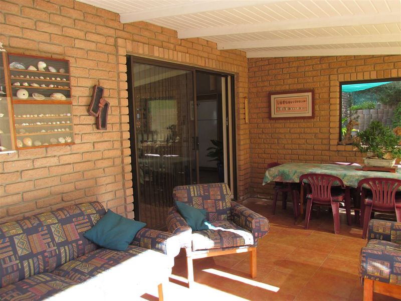 A covered outdoor patio area featuring exposed brick walls, tiled flooring, and sliding glass doors providing access to the interior living space.