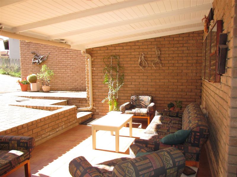 A covered outdoor patio featuring exposed brick walls, a timber-lined ceiling, and tiled flooring, providing a functional space for outdoor relaxation.