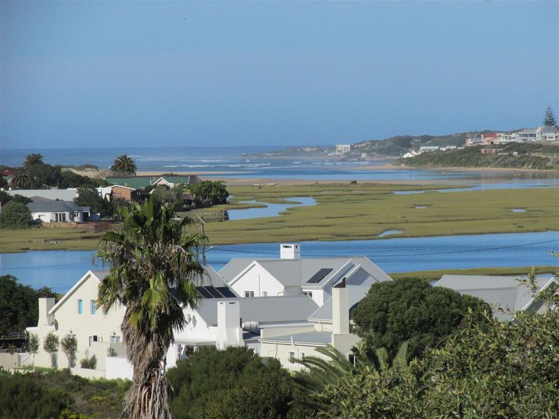 Elevated scenic view overlooking a coastal estuary, wetlands, and surrounding residential properties with visible roof structures.