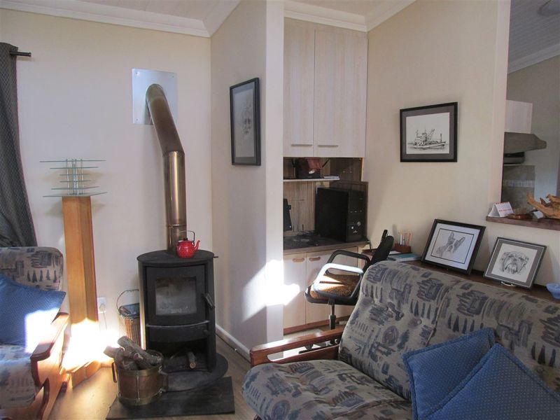 Cozy living room featuring a freestanding fireplace, built-in cabinetry, and laminate flooring, offering a warm and functional space.