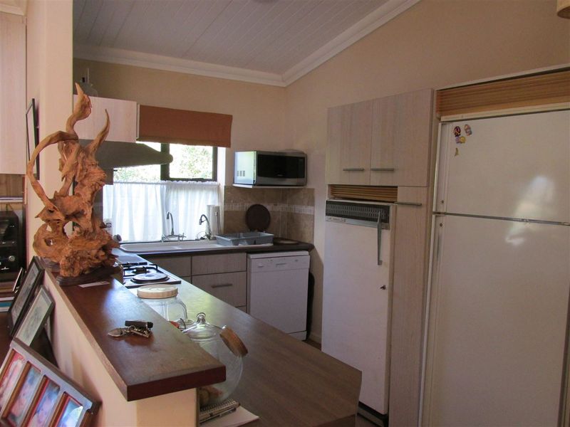 A functional kitchen featuring built-in cabinetry, laminate countertops, a built-in hob with extractor, and a tongue and groove ceiling finish.