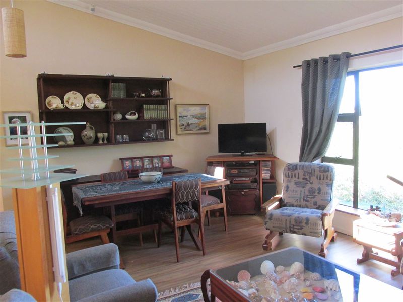 A living room featuring laminate flooring, coved ceilings, and a large window allowing natural light into the space.