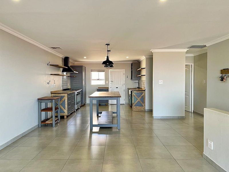 Spacious open-plan kitchen featuring custom cabinetry, a central island, modern appliances, and neutral tiled flooring, creating a functional and inviting living space.