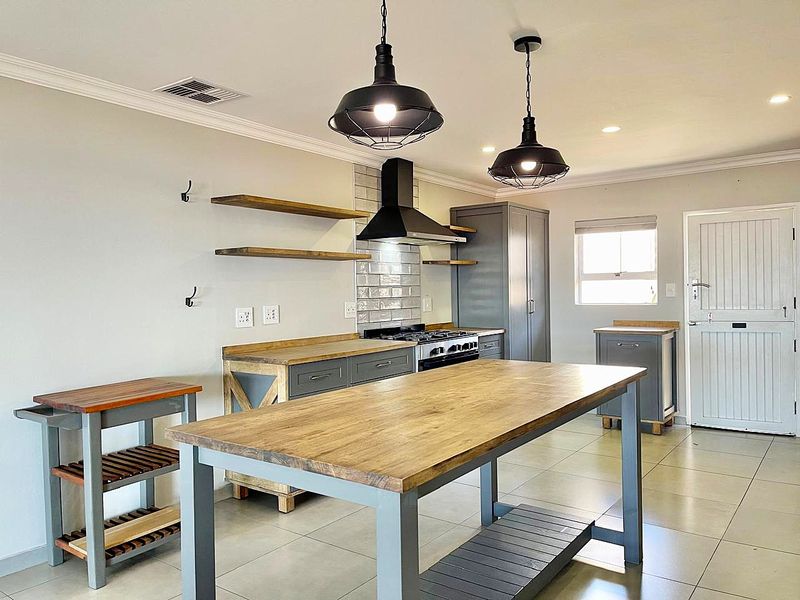 Modern kitchen featuring grey cabinetry, wooden countertops, subway tile backsplash, gas stove with extractor fan, and stylish pendant lighting.