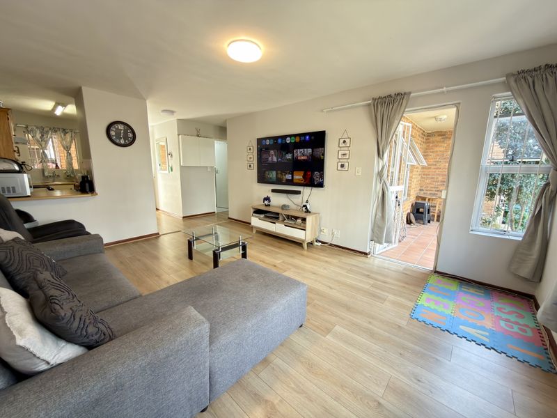 Open-plan living area featuring laminate flooring, neutral walls, and direct access to an outdoor patio space.