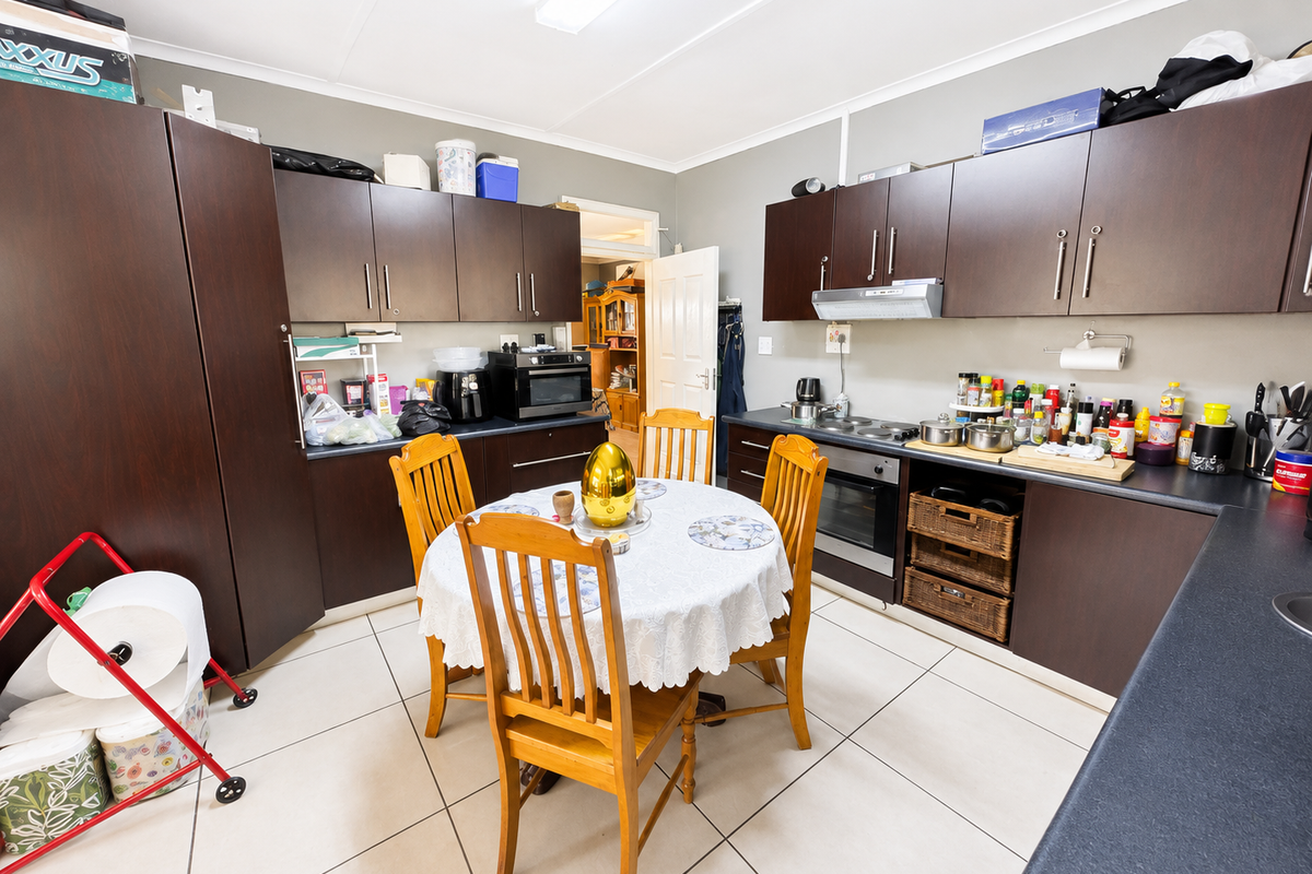 A functional kitchen featuring dark wood cabinetry, built-in oven, electric hob, and tiled flooring, offering a practical layout for daily meal preparation.