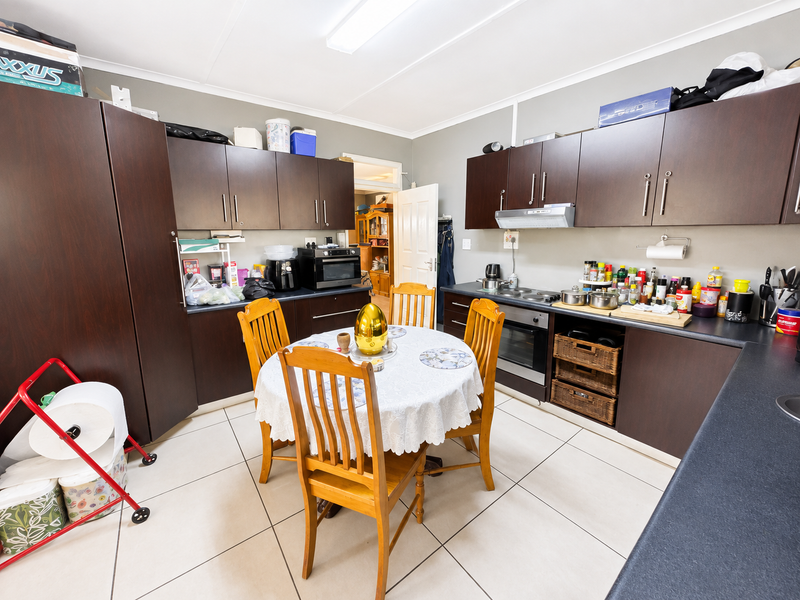 A functional kitchen featuring dark wood cabinetry, built-in oven, electric hob, and tiled flooring, offering a practical layout for daily meal preparation.