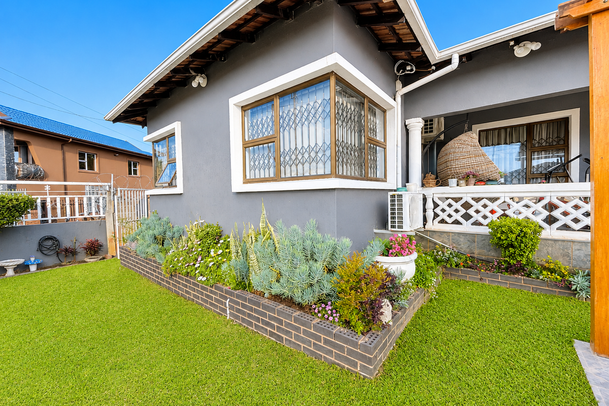 A well-maintained rear exterior view featuring a landscaped brick planter box, a covered patio area with a timber pergola, and secure window fittings.
