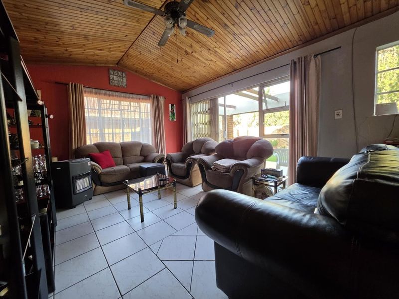 Spacious living room featuring a vaulted timber-clad ceiling, tiled flooring, and large sliding glass doors providing natural light and access to the outdoor area.