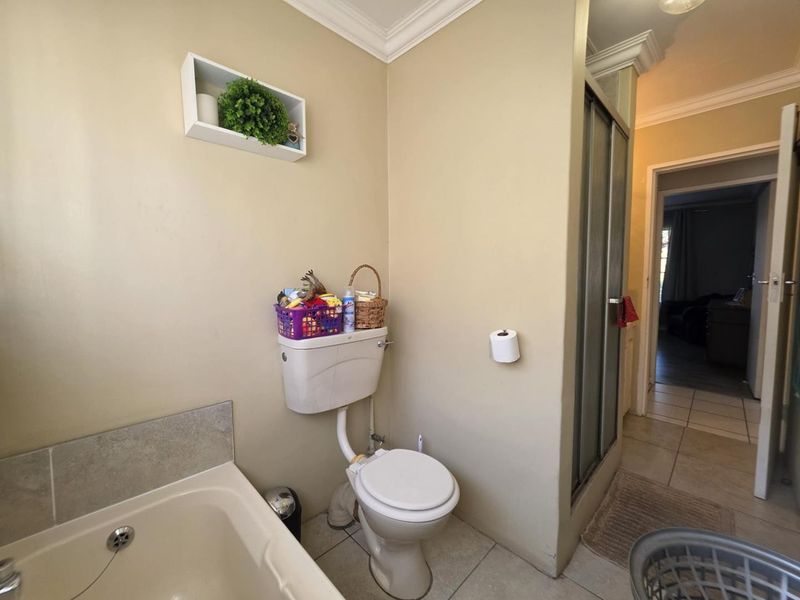 A functional bathroom featuring a bathtub, toilet, and separate shower enclosure with tiled flooring and crown molding details.