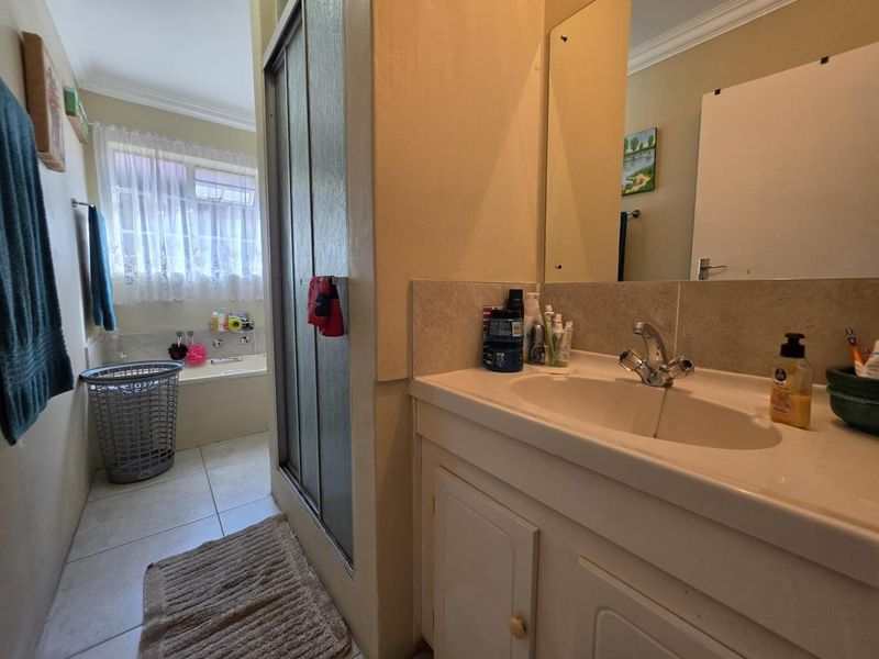 A functional bathroom featuring a vanity with basin, a separate shower enclosure, and a bathtub, finished with neutral floor tiles.