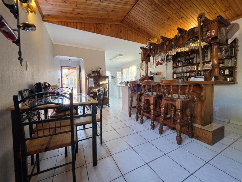 A dedicated bar area featuring a built-in wooden bar counter, timber-clad vaulted ceiling, and ceramic floor tiles, offering a classic entertainment space.
