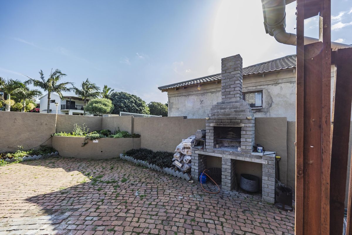 Rear courtyard featuring a built-in brick braai, paved patio area, and raised garden beds, offering a functional outdoor entertainment space.