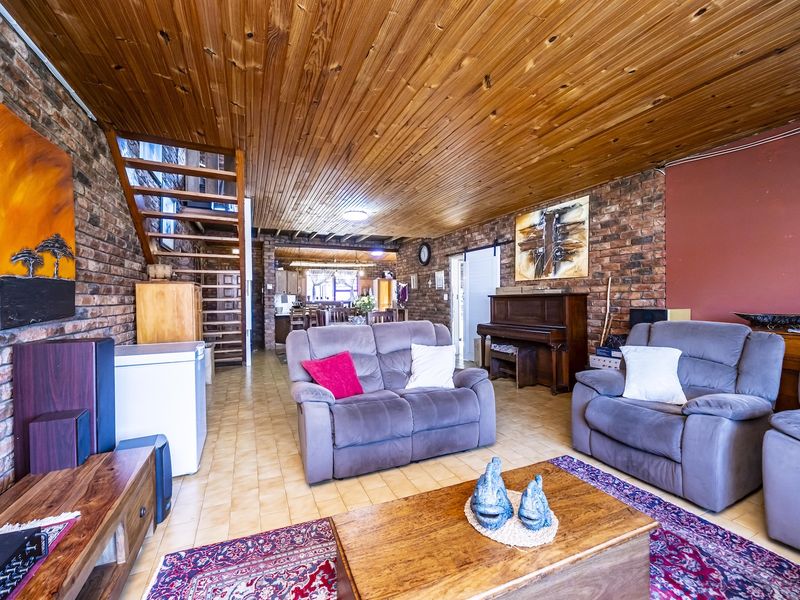Spacious open-plan living area featuring exposed brick walls, a timber-clad ceiling, and a staircase leading to the upper level.