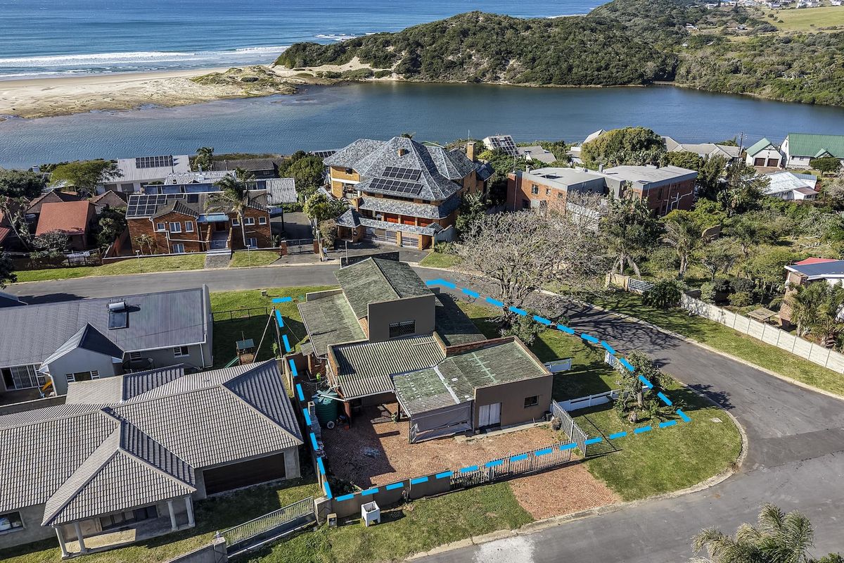 Aerial view of the property highlighting the roof structure, fenced yard, and surrounding coastal neighborhood landscape.