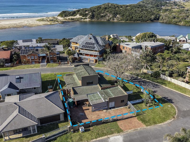 Aerial view of the property highlighting the roof structure, fenced yard, and surrounding coastal neighborhood landscape.