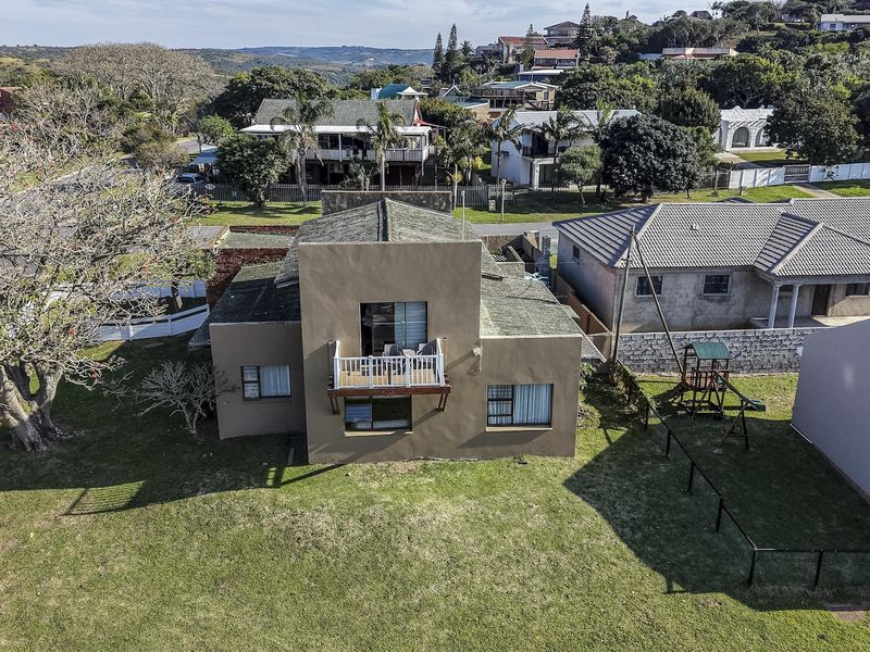 Aerial view of a detached residential property featuring a tiled roof, a balcony with railing, and surrounding garden space in a suburban neighborhood.