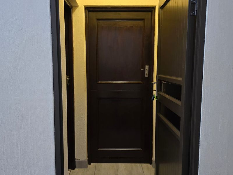 A clean and well-maintained entryway featuring tiled flooring and a dark wood door, providing a simple and functional transition space.