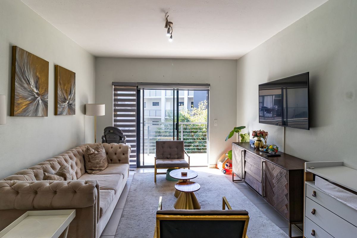 A well-lit living room featuring tiled flooring and a sliding glass door that opens to a balcony, providing natural light and outdoor access.