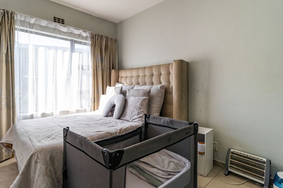 A functional bedroom featuring tiled flooring and large windows with curtain tracks, providing natural light and a neutral backdrop for personalization.