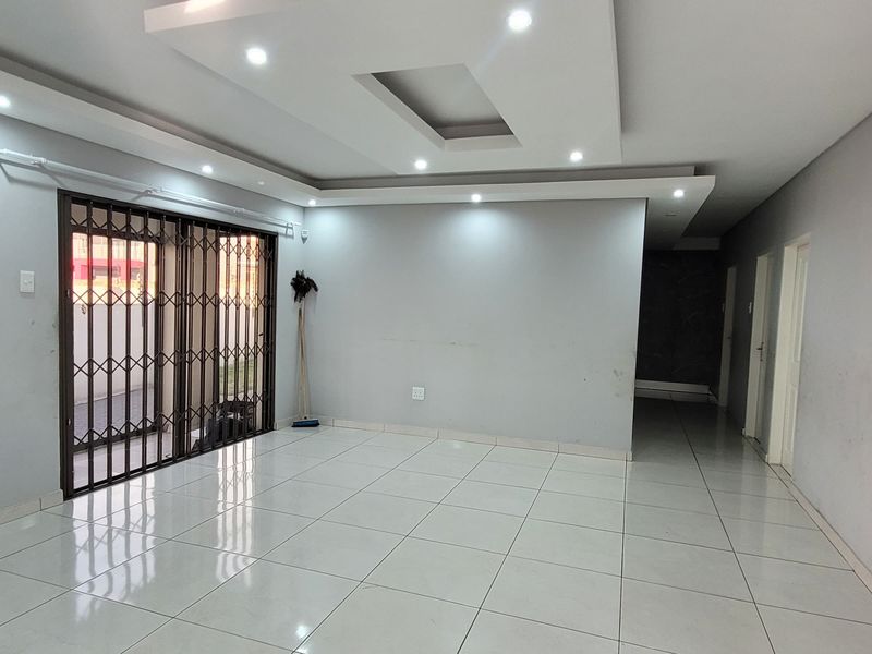 Spacious, empty living area featuring modern recessed ceiling lighting, large format floor tiles, and secure sliding door access.