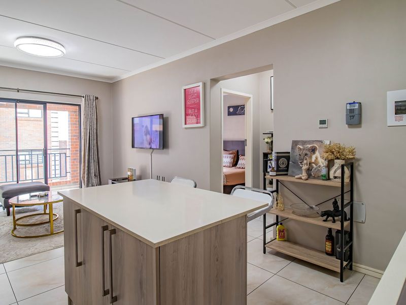 Modern open-plan living area featuring a central kitchen island, tiled flooring, and a sliding door leading to a private balcony.