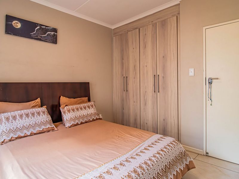 A well-maintained bedroom featuring neutral wall tones, tiled flooring, and ample built-in cupboard storage.
