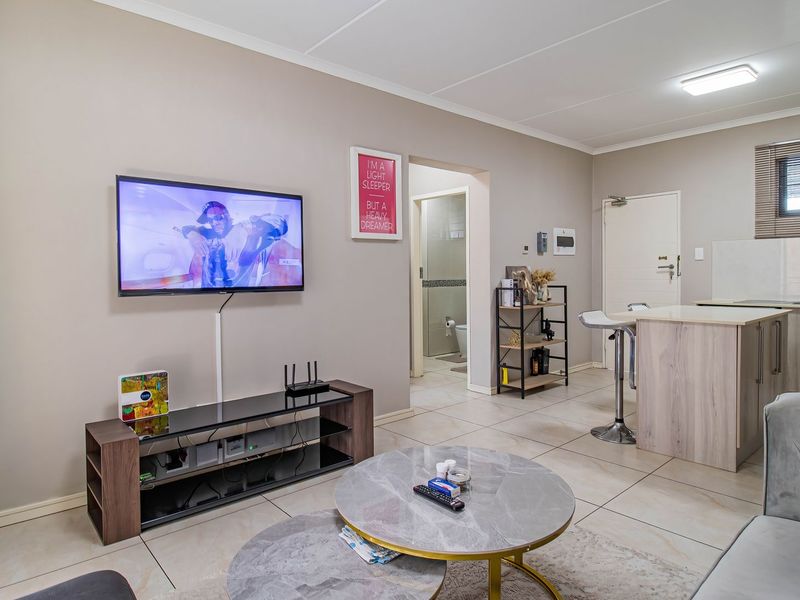 Open-plan living area featuring a modern kitchen with a central island, tiled flooring, and neutral wall tones, providing a functional and cohesive living space.