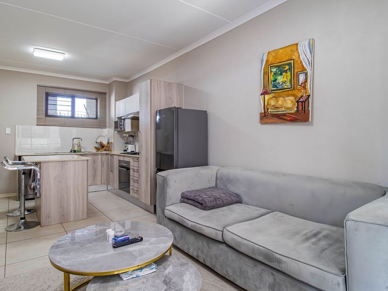 Open-plan living area featuring a modern kitchen with built-in cabinetry, integrated appliances, a central island, and tiled flooring throughout.