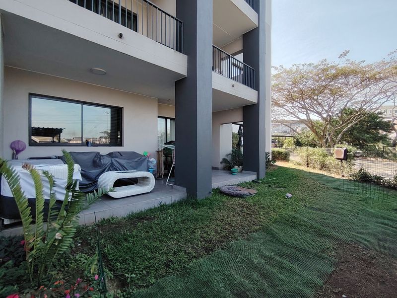 A ground floor covered patio area featuring tiled flooring, metal railings, and direct access to a private garden space.