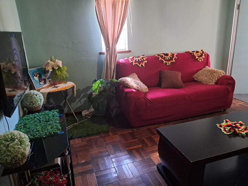 A living room featuring traditional parquet flooring and a window, offering a functional space with potential for cosmetic updates.