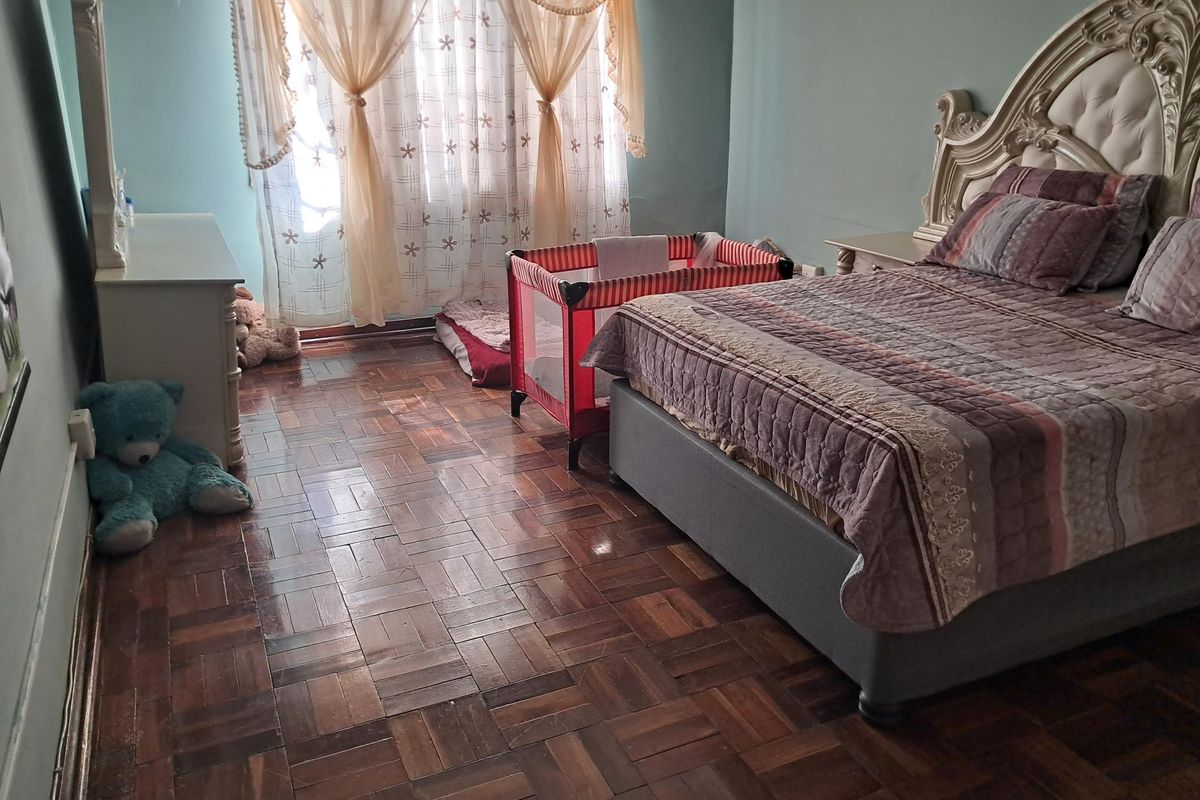 A bedroom featuring classic parquet wood flooring and access to a balcony through a sliding glass door.