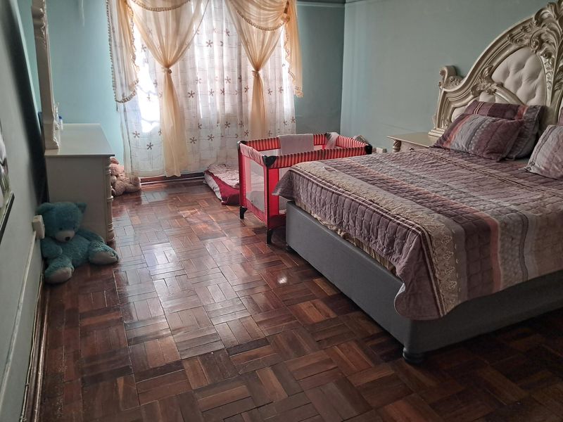 A bedroom featuring classic parquet wood flooring and access to a balcony through a sliding glass door.