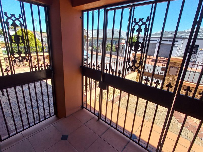 Secure gated entrance area featuring tiled flooring and wrought iron security gates, providing access to the property exterior.