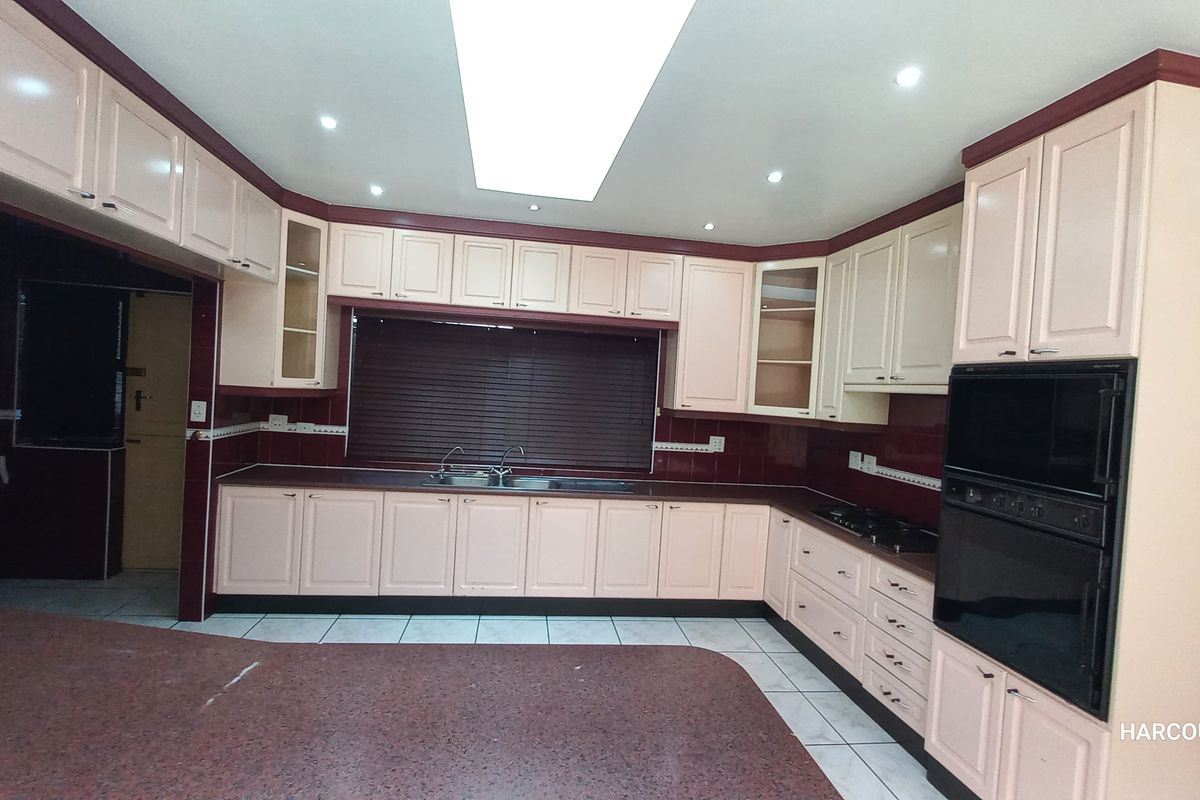 Spacious kitchen featuring extensive built-in cabinetry, granite countertops, integrated oven, and hob, with a functional layout and recessed lighting.