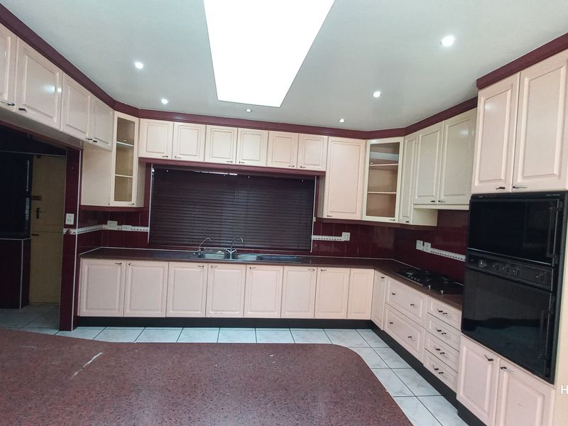 Spacious kitchen featuring extensive built-in cabinetry, granite countertops, integrated oven, and hob, with a functional layout and recessed lighting.