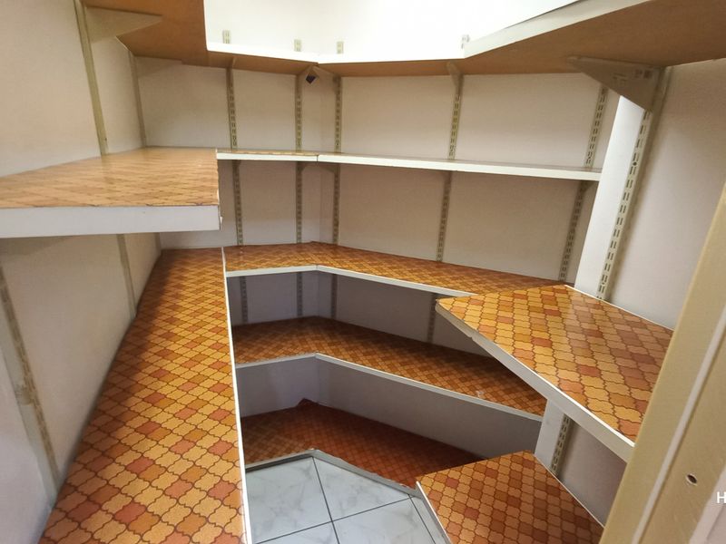 A walk-in pantry or scullery area featuring multiple levels of built-in shelving with adjustable tracks and tiled flooring.